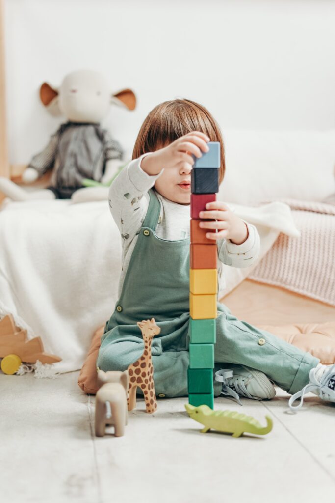 Child in white long sleeve top and dungaree trousers playing in a childcare cleaned by vipfs